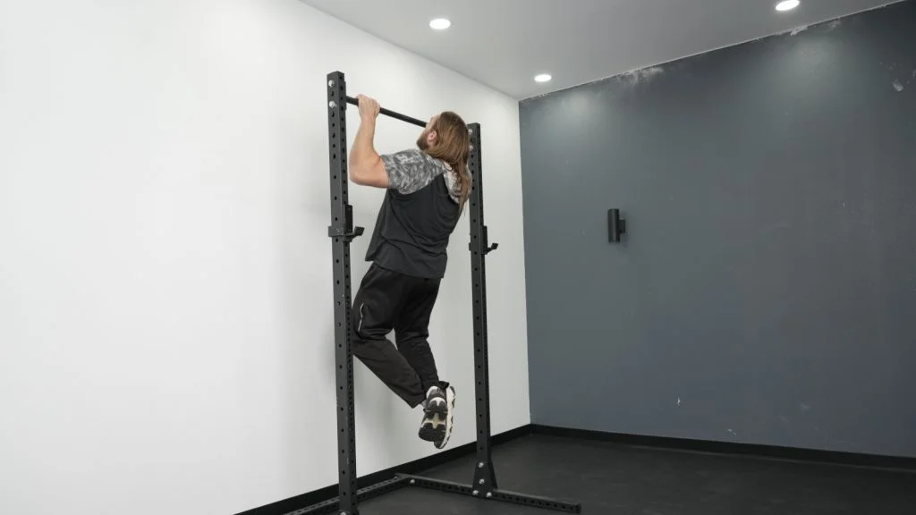 fringe-sport-unlimited-squat-pullup-rack-side-full-view-pullup A person doing a pull-up on the Fringe Sport Unlimited Squat Stand with Pull-Up Bar.