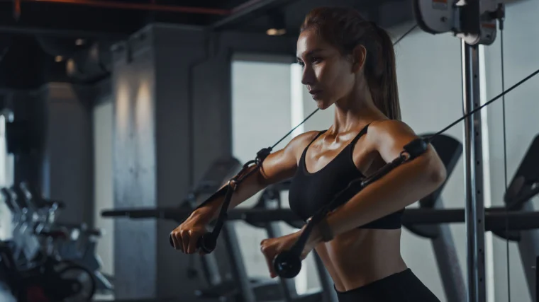 A person doing resistance training using a cable machine.