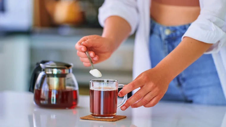 A person adding sweetener to their drink.