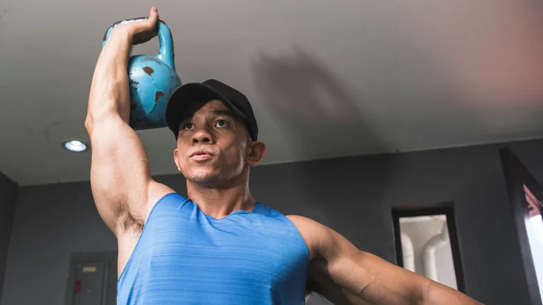 A person presses a kettlebell overhead.