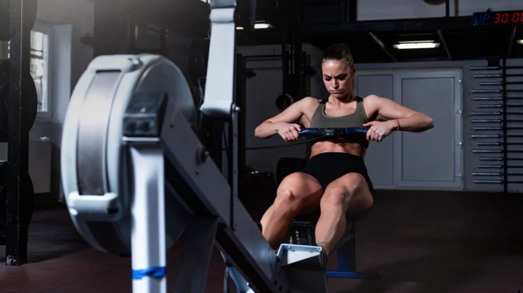 A fit person working out in the gym on a rowing machine.