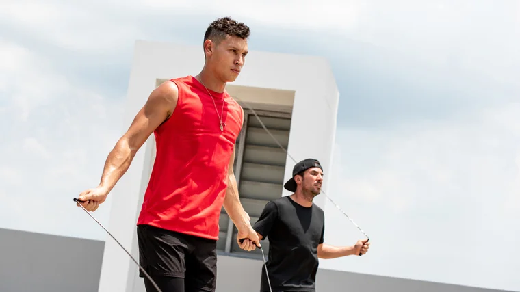 Two people jump rope outside.