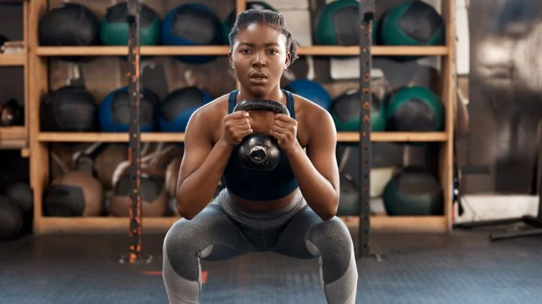 A person doing squats with a kettlebell.