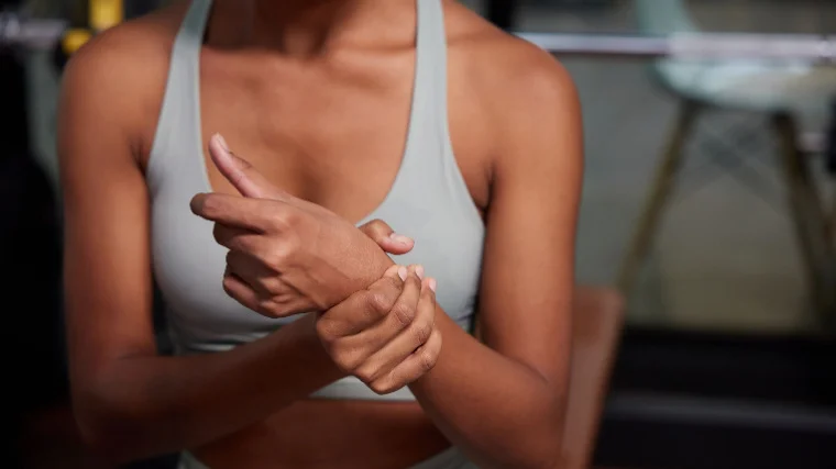A close up young sporty person feeling pain in the wrist from their workout in the gym.