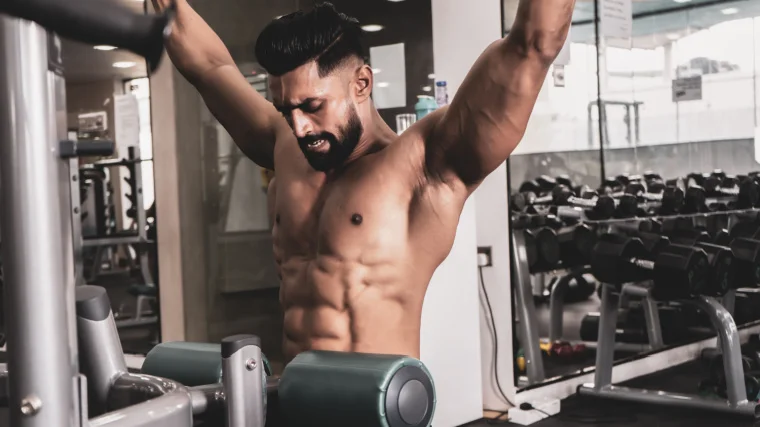 A shirtless athlete performs a lat pulldown.