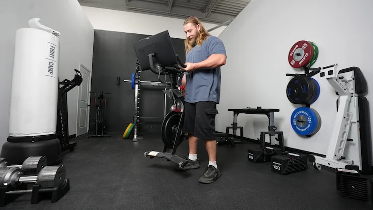 A BarBend tester setting up the Original Peloton Bike for a workout