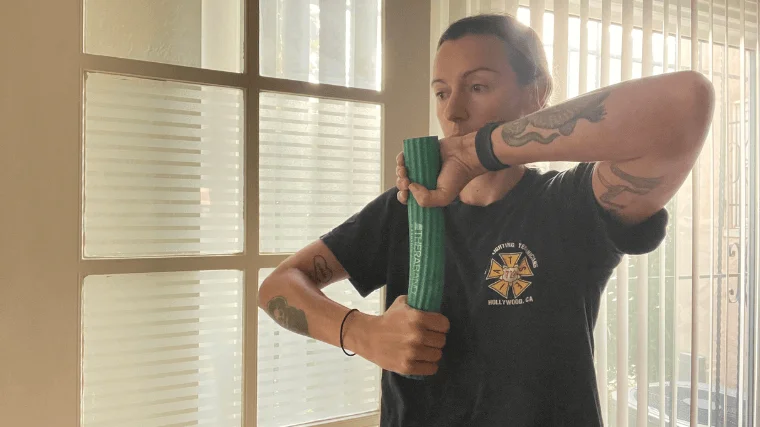 woamn uses theraband flexbar for climbers elbow starting position