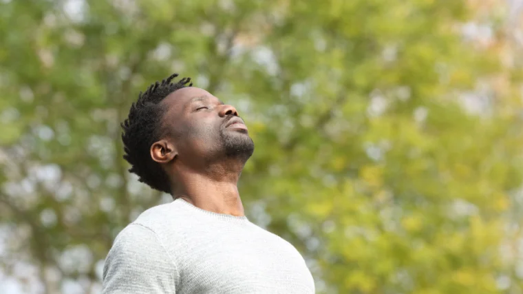 A man outdoor taking the nature in and breathing deep.
