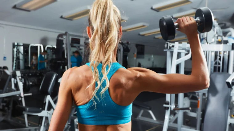 The back of a person raising a dumbbell with one arm.