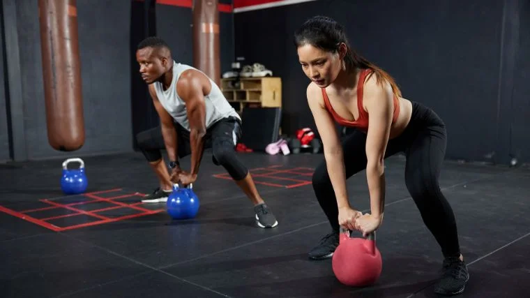 A couple of people working out with kettlebells.