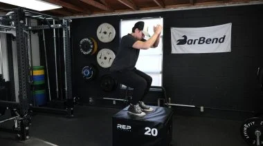 A BarBend tester doing the box jump on a plyo box, as it is one of the best agility training exercises.