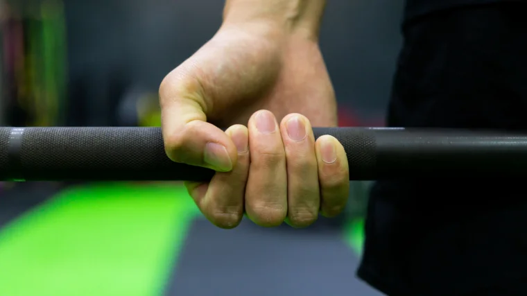 A person picks up a barbell with a supinated grip.