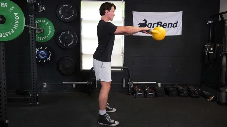 Jake doing kettlebell swings in the BarBend gym. 