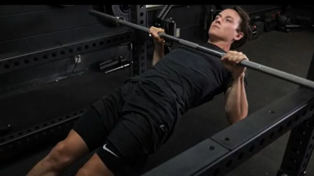 A person performing the barbell inverted row exercise.