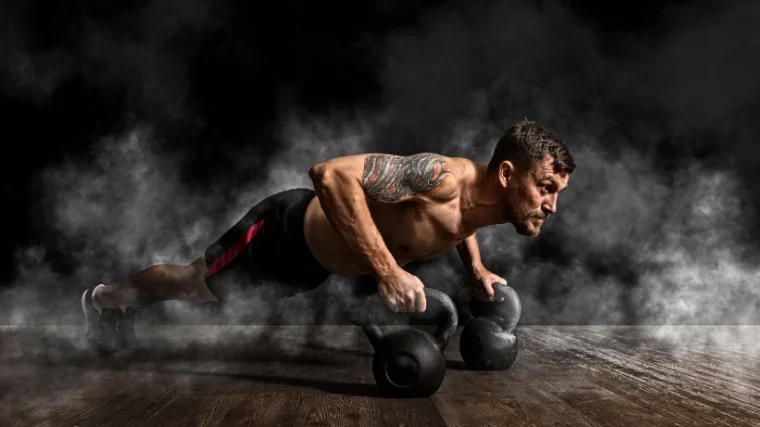 A muscular person doing push ups on kettlebells in the gym.