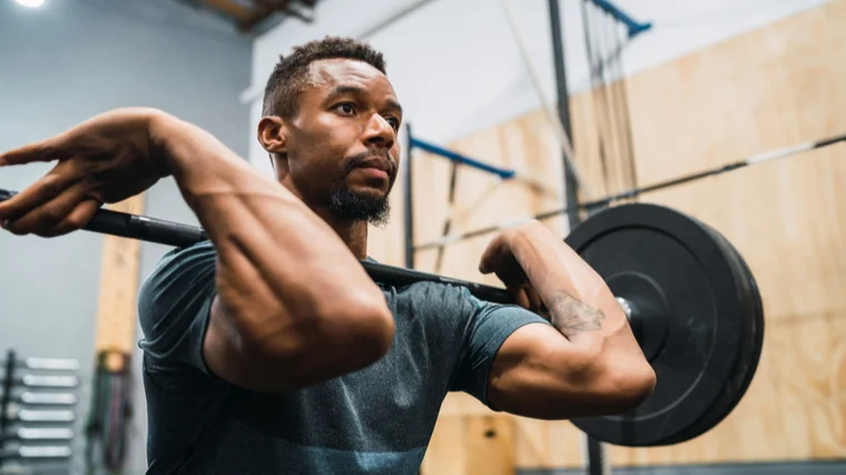 A person holds a loaded barbell in the front rack position.