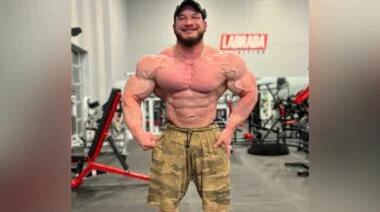 Shirtless man wearing camo shirts, flexing in a most muscular position