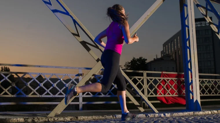 A person in sportswear running in the morning while it is still dark.
