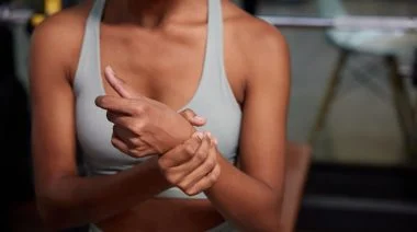 A close up young sporty person feeling pain in the wrist from their workout in the gym.