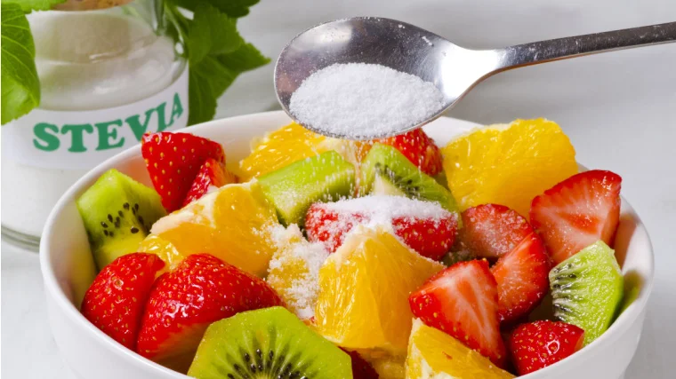 A person pouring sweetener on their salad.