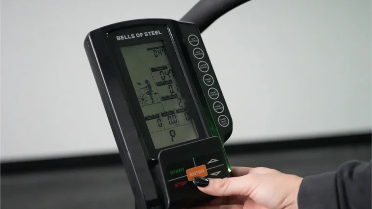 Our tester adjusting the monitor controls on the Bells of Steel Blitz Air Bike 2.0.