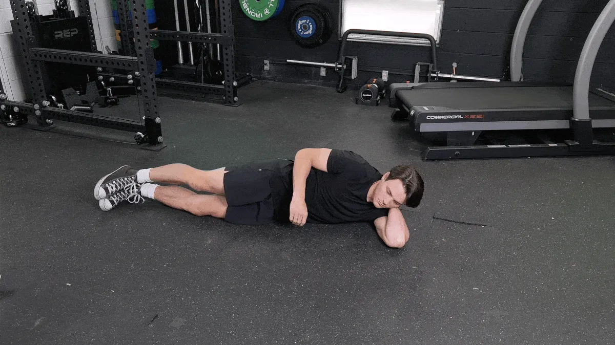 BarBend's Jake Herod performing the lying quad stretch.