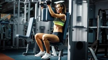 A person in neon green and black sports bra doing a seated chest flye.