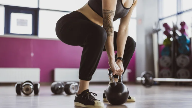 A person deadlifting a kettlebell in the gym.