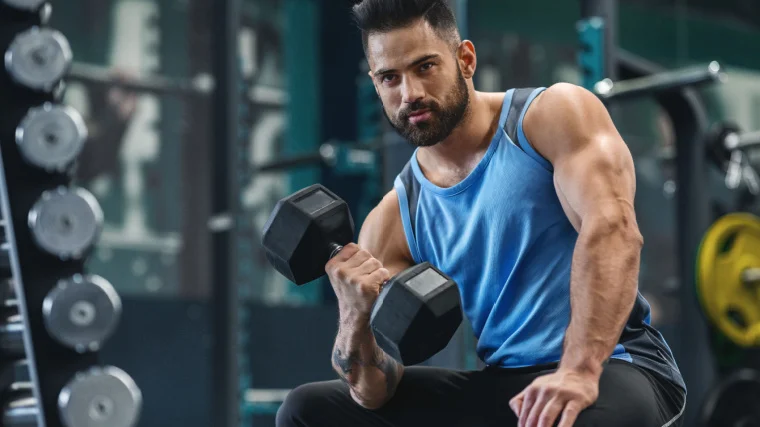 A bodybuilder picking up a dumbbell at the gym.