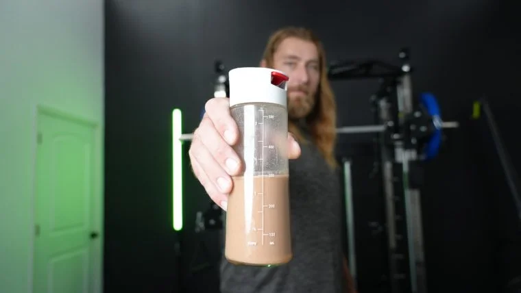 Copy of kos vegan protein powder holding bottle up e1713208459521