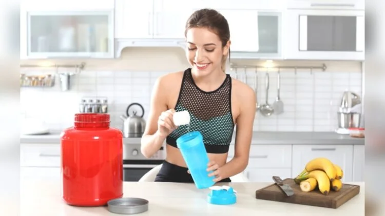 A person scooping creatine powder into her tumbler.