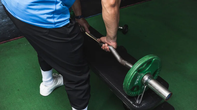 A person picks up an EZ bar with a pronated grip.