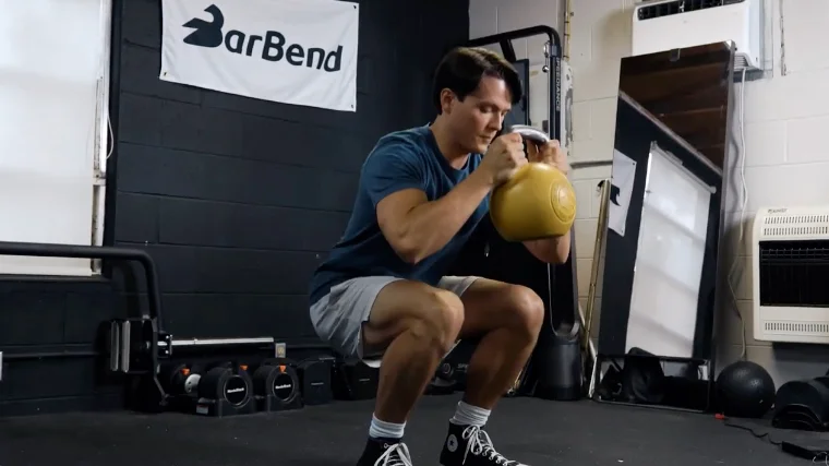 A fit person performing the goblet squat exercise.