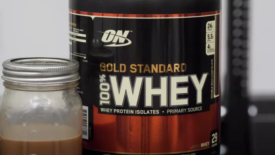 An Extreme Milk Chocolate flavored Optimum Nutrition Whey Protein shake next to the container.