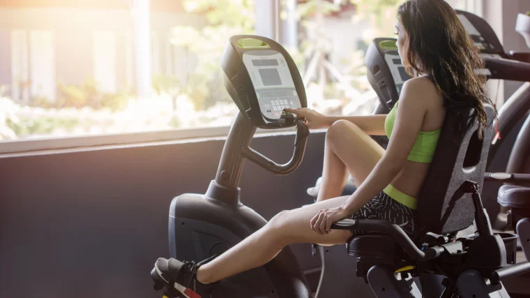A person on a recumbent bike in the gym. 