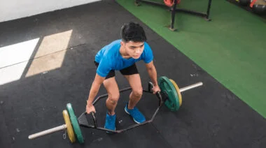 A person prepares to perform a trap bar deadlift.