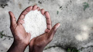 A person holds white rice in their cupped hands.