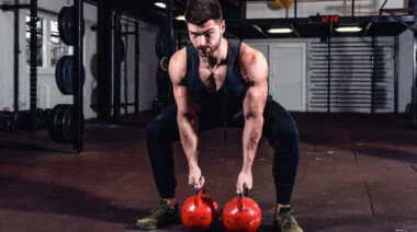 A person prepares to perform a double kettlebell swing.