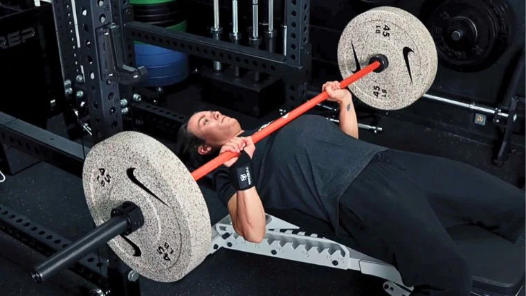 BarBend's Jake Herod bench pressing a barbell in the gym.
