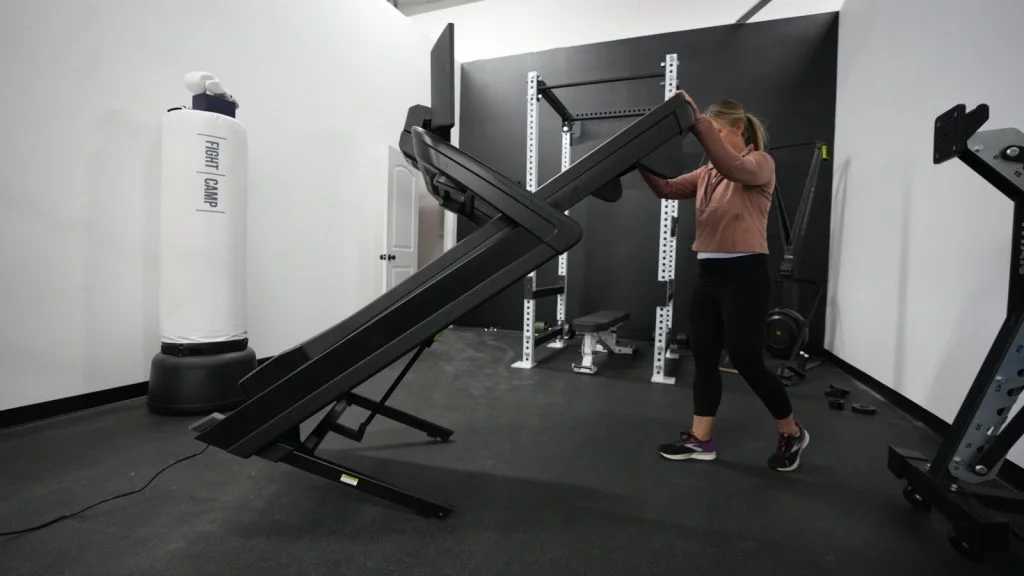 Side biew of a person unfolding the NordicTrack 1750 treadmill.