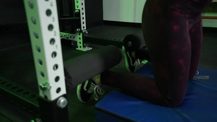rep-fitness-leg-roller-attachment-close-up-legs-under-roller A close look at the REP Fitness Leg Roller Attachment with our tester's legs under the rollers