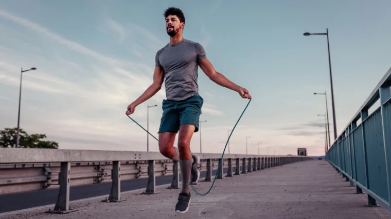 A fit person exercising with a jumping rope outdoors.