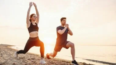 A couple doing lunges on the beach.