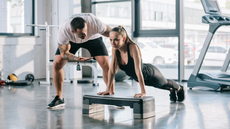 A personal trainer correcting someone's incline push-up form.