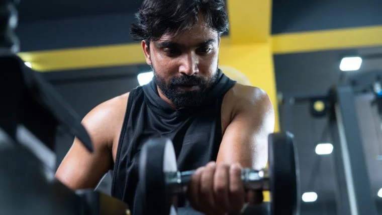 A muscular person doing wrist curls with a dumbbell.