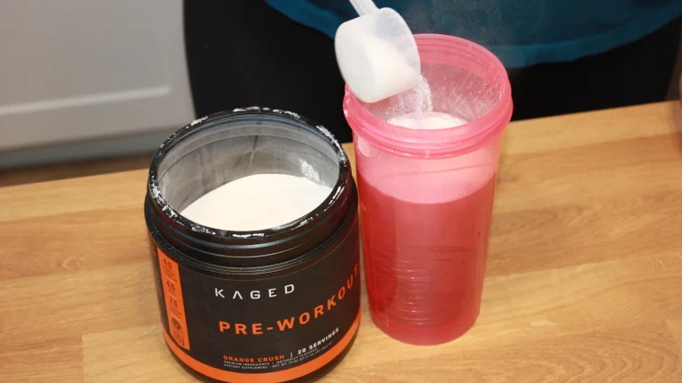 Pouring a scoop of Kaged Muscle Pre-Workout into a shaker cup