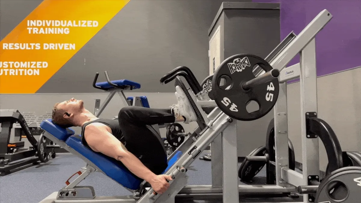 A GIF of a man wearing black sleeveless shirt and black sweatpants performing a rep of leg presses on an angled Nautilus leg press machine.  