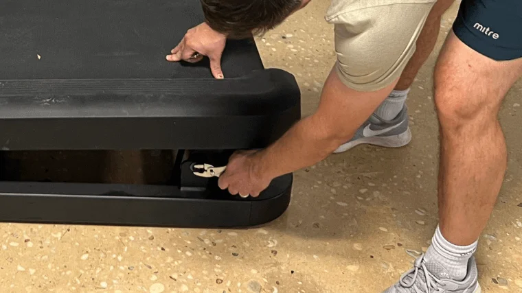 Our expert removes the rear tension bolts to access the treadmill belt.