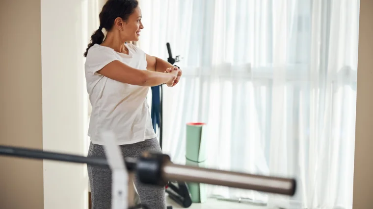 A woman stretching and rotating torso inside home gym .
