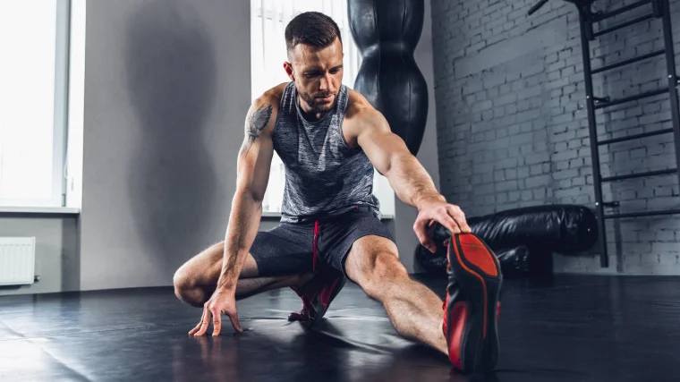 A muscular person stretching their legs.